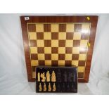 A chess set with wooden board measuring 62 cm x 62 cm.