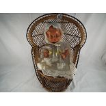 A good quality child's wicker chair with a child's doll with painted eyes. Doll approx. 38 cm high.