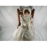 A good quality wooden child's chair with a child's doll with bisque head, glass eyes,