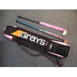 A Grays hockey stick bag containing 2 hockey sticks by Piranha and Olympus.