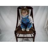 A good quality wicker and wood child's chair with a child's doll with bisque head, glass eyes,