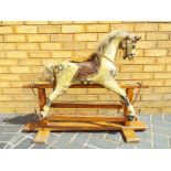 A wooden child's rocking horse on a wooden base approximately 80 cm (h)