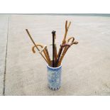 An Asian ceramic umbrella stand containing 12 walking canes/sticks.