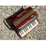 A Bell two octave accordian, the red marbled body with plaque marked Bell Musical Instruments Ltd,