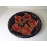 Moorcroft Pottery - a shallow bowl decorated with pomegranate on a blue ground, signed to the base,
