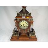 An unusual carved wooden mantel clock in the form of a castle with applied brass mount fences and