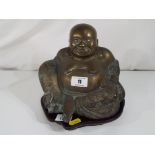 A brass figure of a Buddha on wooden stand.