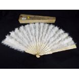 An early 20 th century ivory fan with pierced decoration and adorned with white feathers, in case.
