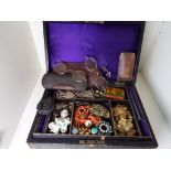 An early 20th century black leather jewellery case containing a selection of period costume