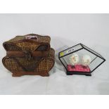 A wooden and woven wicker basket and a pair of Asian style blown hand-painted eggs in glass display