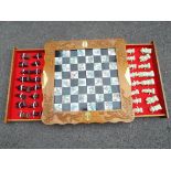 A Chess Set comprising hinged board with Asian decoration to the squares above two drawers of