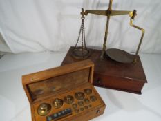 A brass weighing balance and a cased set of graduated weights