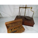 A brass weighing balance and a cased set of graduated weights