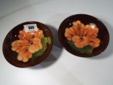 Moorcroft Pottery - a pair of small pedestal bowls decorated with pink coral hibiscus on a brown