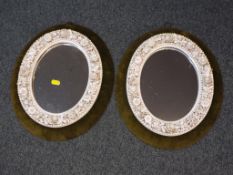 A pair of Victorian oval framed mirrors, the frames with floral and foliate borders,