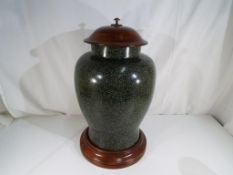 A large lidded urn with solid wooden plinth and matching lid,
