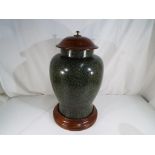 A large lidded urn with solid wooden plinth and matching lid,