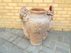 A very large twin handled terracotta urn with relief decoration depicting a pair of bearded dragons,