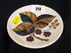 Moorcroft - a Moorcroft pottery pin dish in the leaf and berry pattern, approximate diameter 12 cm.