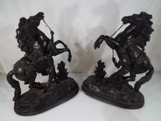 A pair of black painted spelter Marley horse groups on wooden stands,