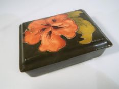 Moorcroft Pottery - a lidded rectangular dish decorated with pink coral hibiscus on a green ground