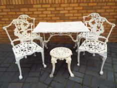 A cast aluminium garden table with four chairs and a stool,