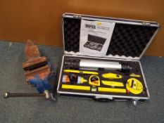 A vice and a hard case containing a Torq Laser Level tool kit,