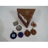 A triangular inlaid wooden box with a small quantity of predominantly dancing medals.