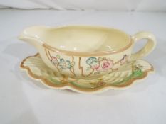 Clarice Cliff - A Clarice Cliff sauce boat and matching under plate, decorated in a floral pattern.