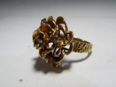 A lady's hallmarked 18 carat gold flower ring set with a central 15 pt brilliant cut diamond and a