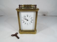 A Victorian brass and glass striking French carriage clock with open dial and key.