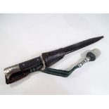 A WW2 German dress bayonet marked to the blade WKC with black chequered grips and metal scabbard