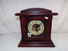 A modern mahogany cased mantel clock with Arabic numerals on a yellow metal dial with pendulum and
