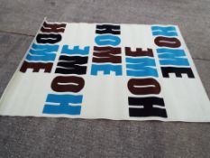 Unused retail stock - A modern floor rug decorated with the word "Home" on a cream ground.