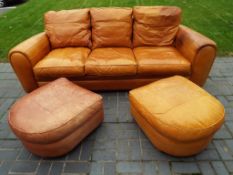 A good quality leather three seater sofa with two footstools, 95 cm (h) x 235 cm (w) x 107 cm (d).