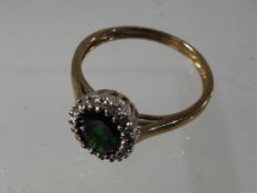 A lady's 9 carat yellow gold qvc cluster ring set with a green central stone surrounded by 8-cut