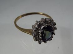 A lady's 9 carat yellow gold cluster ring set with a blue synthetic central stone surrounded by cz,