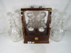 A tantalus with brass mounts, two decanters and bottle labels,