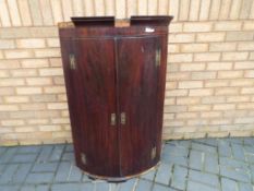 A Georgian bow front corner cabinet with original fittings,