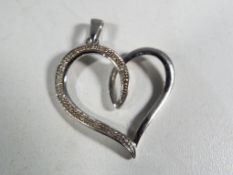 A hallmarked 9 carat white gold and diamond heart pendant.