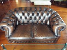 A brown leather button back Chesterfield two seater sofa,