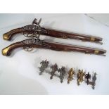 Two replica horse / saddle flintlock pistols and wall hanging brackets.