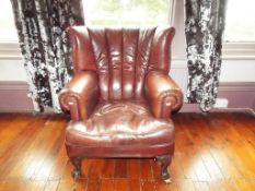 A brown leather button back wing arm chair,