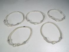 A collection of five silver and pearl bracelets