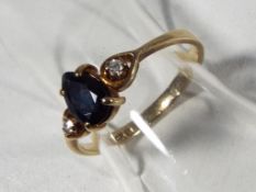 A lady's hallmarked 9 carat gold ring set with a pear shaped sapphire flanked by two diaminds,
