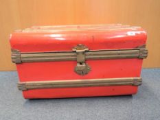 A good quality red and gold metal travel trunk.