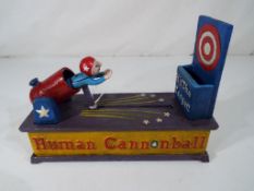 A cast iron money bank in the form of a Human Cannonball,