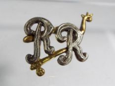A brooch with the initials RR, boxed.