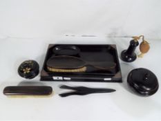 A vintage ebony dressing table set to include brushes, perfume atomiser,