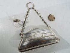 A white metal evening purse with brown fabric fitted interior and chain handle with suspension ring,